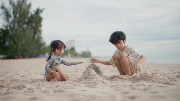 夏天，两个快乐的亚洲男孩和女孩在沙滩上玩耍。