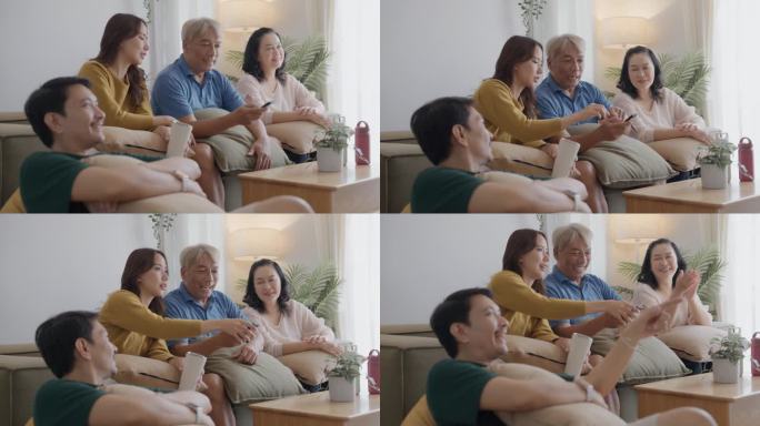多代同堂的家庭一起看电视。爷爷和妈妈、孙女坐在沙发上。