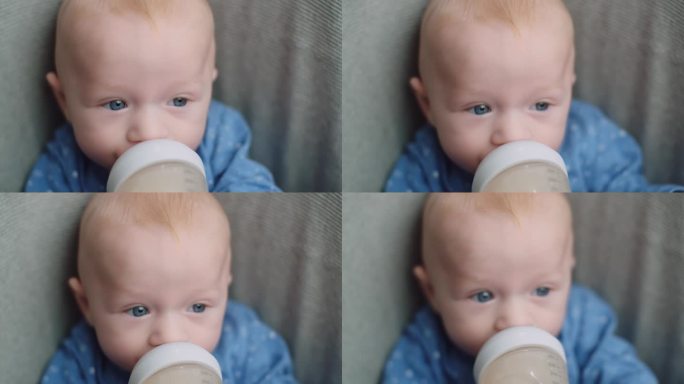在家用奶瓶给小男孩喂奶，肖像婴儿宝宝吃、喝奶粉。