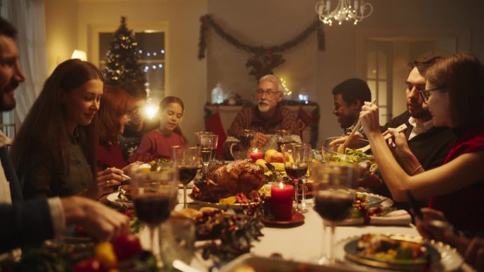 多元文化的亲密朋友和家人一起享受圣诞火鸡晚餐，一起度过冬季周末。节日的夜晚气氛，亲戚共享节日大餐