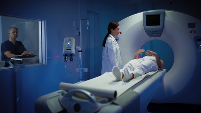 高科技现代医疗设备:在医学实验室男性放射科医生和女性医生控制和监测MRI或CT扫描的女性患者接受健康
