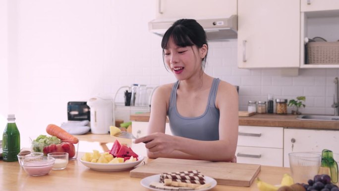 注重健康的亚洲女性穿着运动服，拒绝沉迷于高碳水化合物和高糖的食物，选择水果，以确保她的身体获得营养和