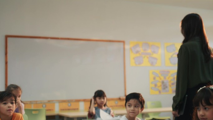 在小学里，老师带领学生走在课桌旁，和孩子们一起上课。