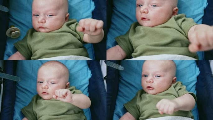 可爱的婴儿躺在婴儿车里，而男性则用手抠奶嘴