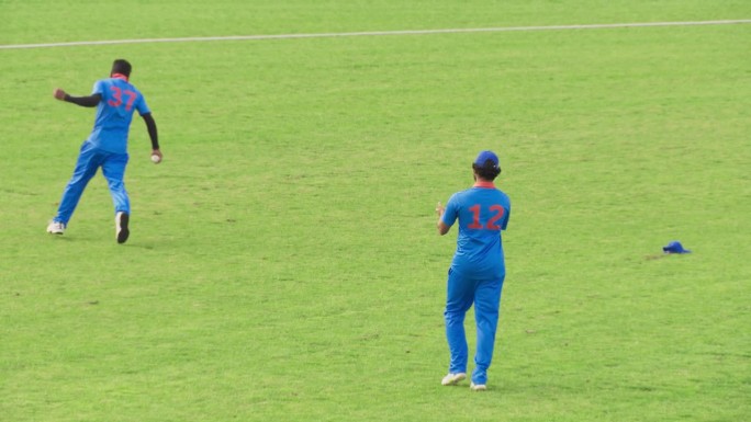 一场职业板球比赛的电视转播画面。印度击球手把球打到空中，对手队的守门员在球未触地的情况下接住球，防止