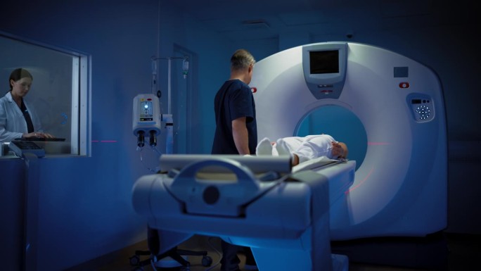 在医学实验室中，女性放射科医生和男性医生控制和监测接受手术的女性患者的MRI或CT扫描。高科技现代医