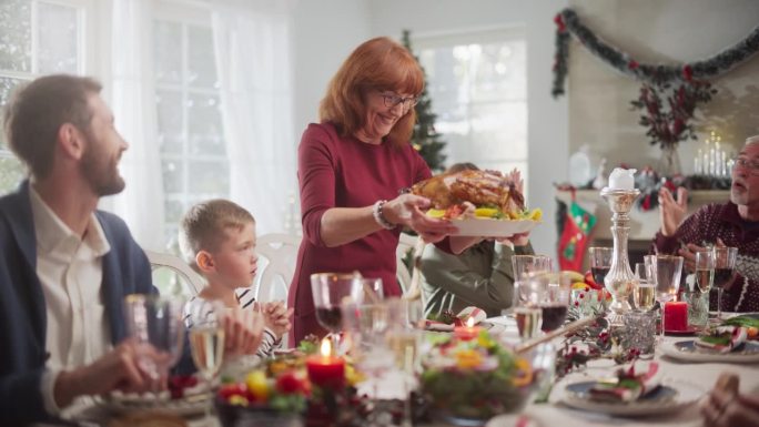 家人和朋友聚在家里吃传统的圣诞晚餐，烤火鸡。客厅里挤满了享用节日菜肴的老人和年轻人。慢动作镜头
