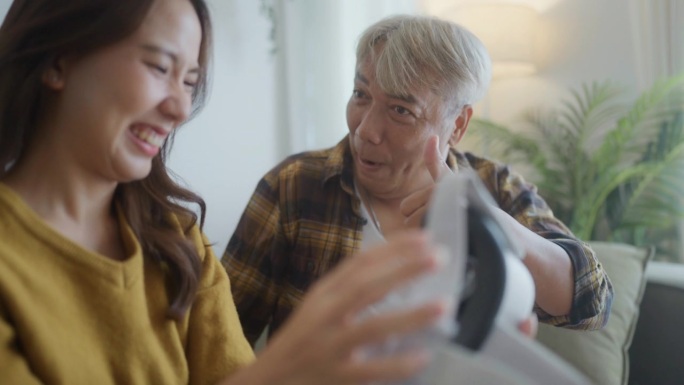 一个积极向上的老人在家里戴着虚拟现实眼镜和他的女儿玩新技术。
