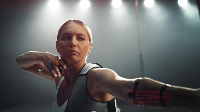 审美超级慢动作镜头的专业女射手在行动。一个美丽的运动员的肖像，拿着弓，拉回箭为了击中目标