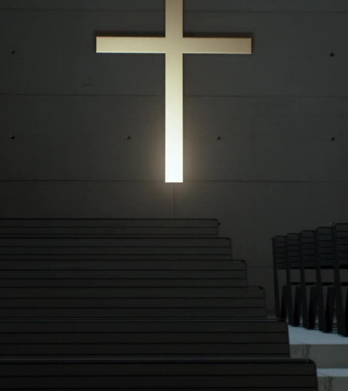十字架嵌在教堂里一排排椅子后面的墙上。