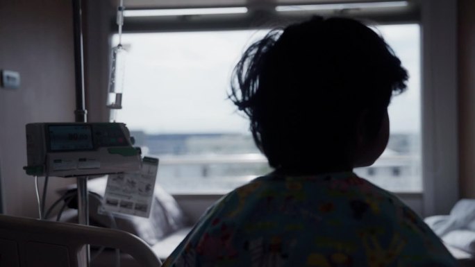 一个患感冒的孩子的剪影望着窗外，住院了。