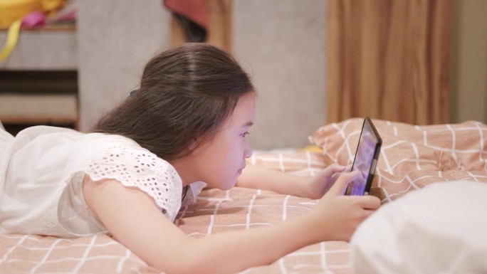 可爱的亚洲女孩在睡觉前用智能手机躺在床上