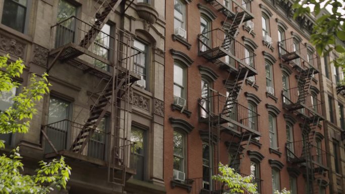 住宅褐石建筑立面在纽约市。旅游视频氛围，镜头与标志性的公寓建筑在一个绿色社区。城市建筑，旅游概念