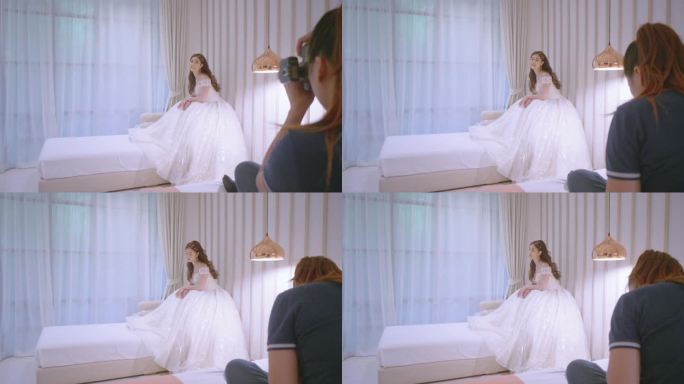 当新娘坐在酒店房间的沙发上时，摄影师正在给她拍照。”