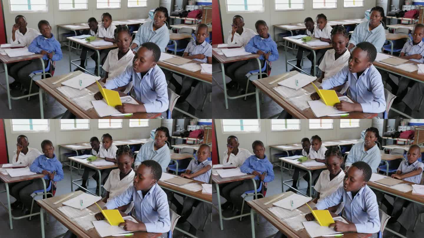 特写镜头。在非洲的一间教室里，一个非洲黑人学生坐在书桌前给全班学生读书