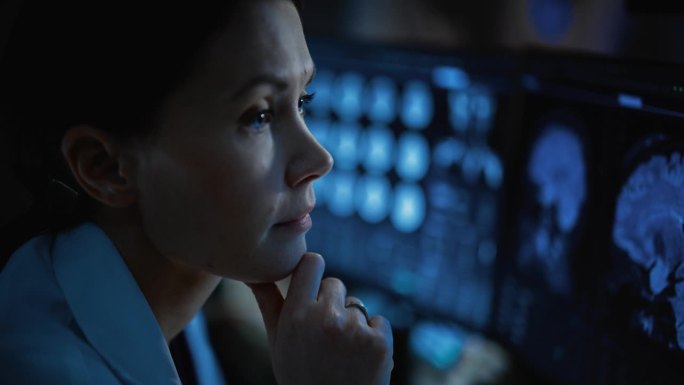 医院研究实验室:专业神经学家分析实时CT扫描诊断病人的特写。女医学家使用计算机与脑扫描MRI图像。