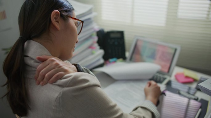 年轻的女商人在现代办公室工作时颈部疼痛