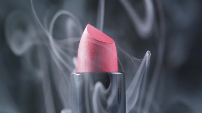 红色口红用烟雾和水滴构成特写背景，不同色调的粉色青铜色口红，工作室广告宏观美容理念。