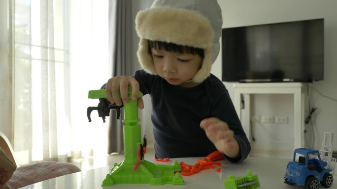 小男孩戴着帽子玩橡皮泥面团和建筑布景，慢动作场景