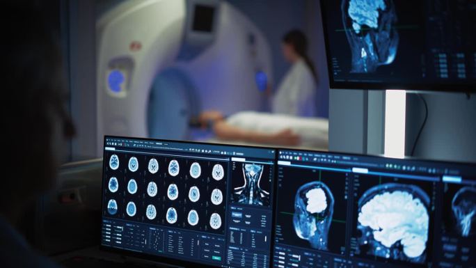 医院研究实验室:男性医学科学家使用计算机与脑扫描MRI图像的女性患者正在接受医疗过程的背景。医疗保健