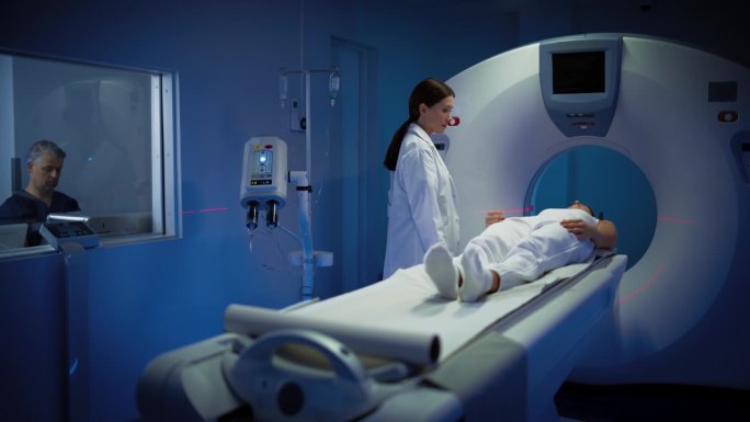 高科技现代医疗设备:在医学实验室男性放射科医生和女性医生控制和监测MRI或CT扫描的女性患者接受健康