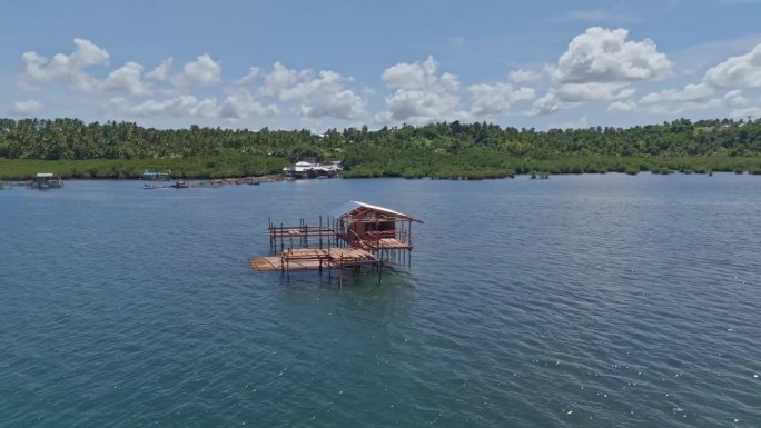 一个独特的木制渔夫小屋，建在浅水区的高跷上，背景是丛林景观。无人机拍摄，白天。巴里巴荣，苏里高市-菲