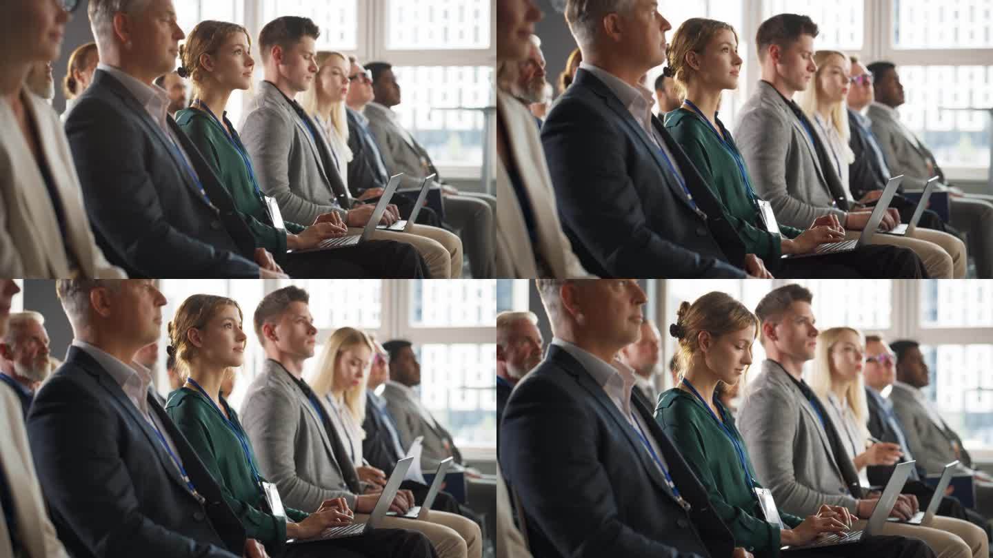 一名年轻女子坐在商务会议拥挤的听众中。微笑着使用笔记本电脑的女代表。经理观看关于投资创新创业公司的激