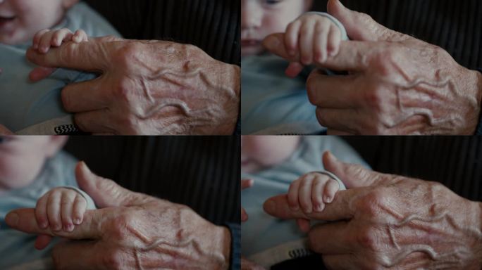 在家里，小男孩的小手握着爷爷的手指