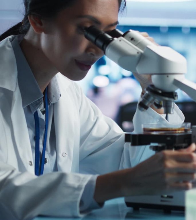 医学发展实验室竖屏:亚洲女科学家用显微镜分析培养皿样品。大型制药实验室与专家进行生物技术研究。