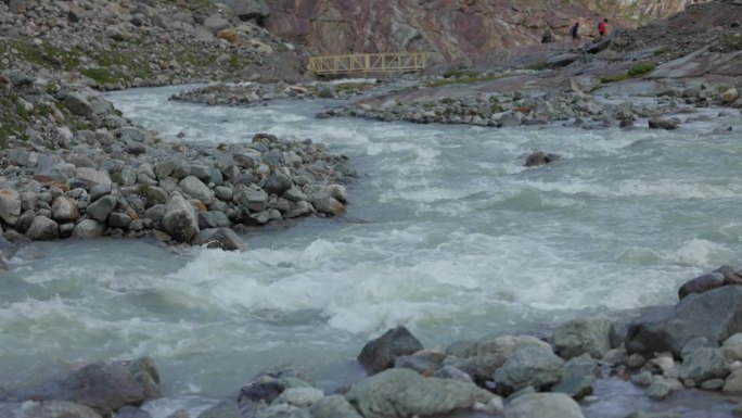 流过费拉里亚冰川附近小岩石的流动河流。慢动作，上移镜头