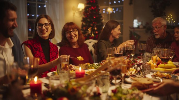 各种各样的亲戚和朋友围坐在餐桌后面，享用美味的饭菜和节日的冬季装饰。快乐的大家庭，愉快的交谈，享受一