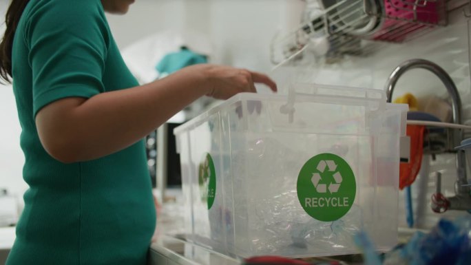 手取塑料瓶，放入垃圾袋准备回收
