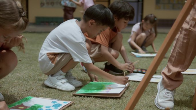 亚洲小学生在学校里和来自不同国家的朋友一起练习在纸上画画。