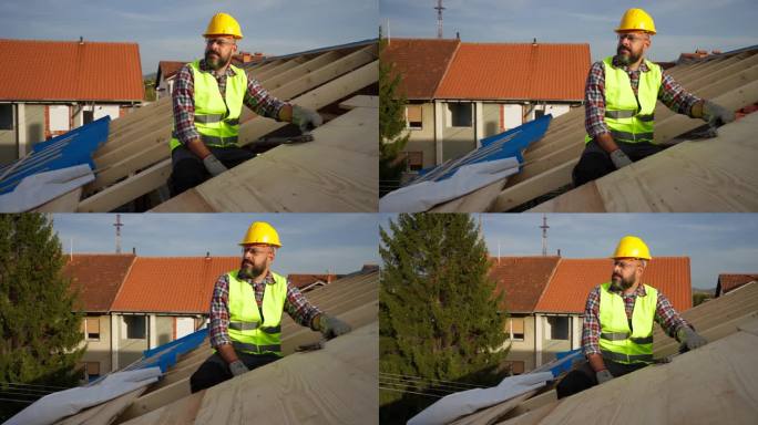 白人男性屋顶工人，在建筑工地的屋顶梁上休息