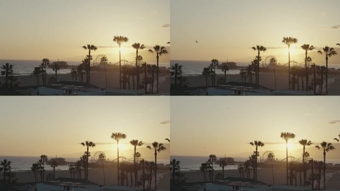 美国洛杉矶圣莫尼卡码头的美丽日落。加州海滩和游乐园地标，棕榈树，海洋，人们在岸边散步