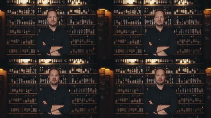 一位成年男性餐厅老板的肖像，背景是一家高档餐厅的酒架上。侍酒师可以提供精品葡萄酒从存储设施。