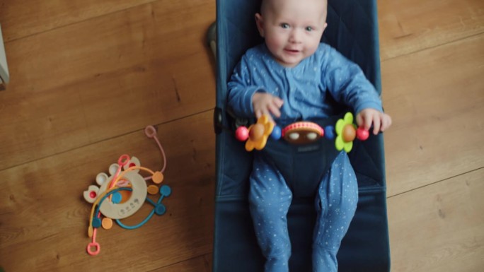 可爱的5个月大的小男孩在蹦床上玩玩具，婴儿活动，孩子在摇椅上玩木制玩具