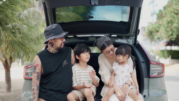 幸福的亚洲家庭坐在汽车后备箱里一起唱歌。