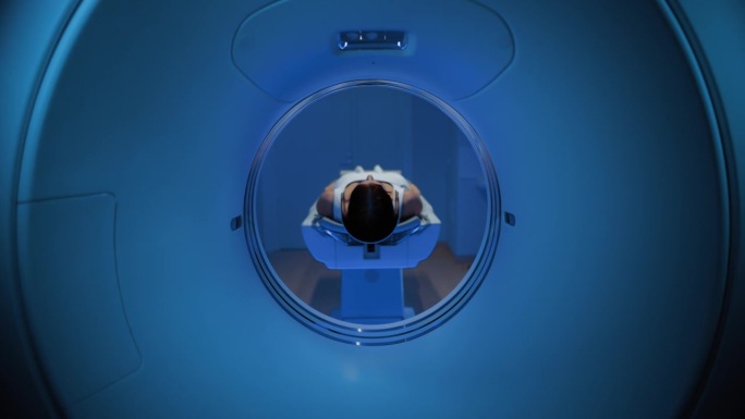 在拥有高科技设备的医学实验室中，躺在CT或MRI扫描床上的匿名女性患者在专业监护下接受扫描程序。床向