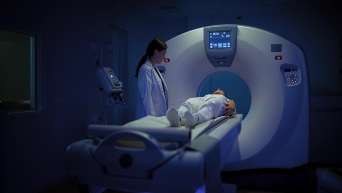 在医学实验室，躺在CT或MRI扫描床上的女性患者在专业放射科医生的监督下接受扫描程序。影像在医学实验