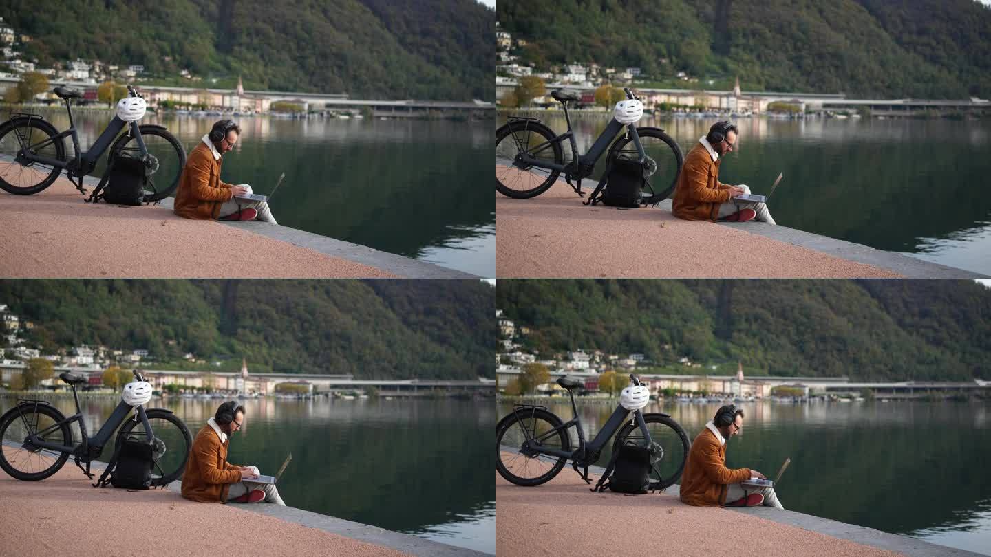 工作与自然相遇:一个人在湖边的木板路上骑着电动自行车和笔记本电脑