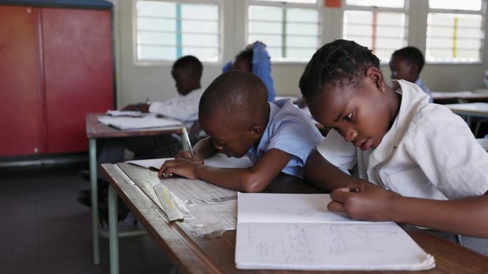 特写镜头。非洲黑人学生在教室的课桌上画画