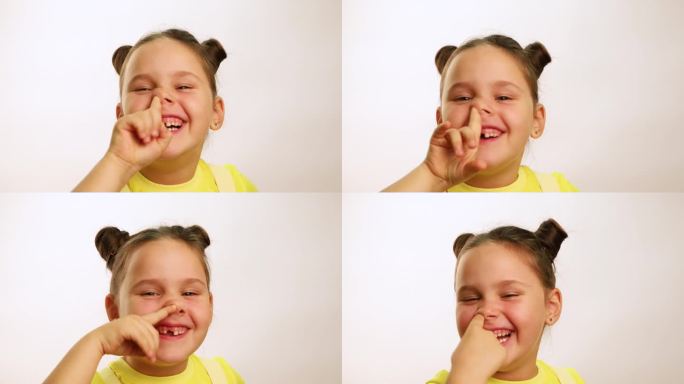 有趣的小女孩笑得很开心，因为牙齿掉了，嘴巴裂开了，抠着鼻子，特写，白色背景。快乐的无牙孩子。健康牙齿