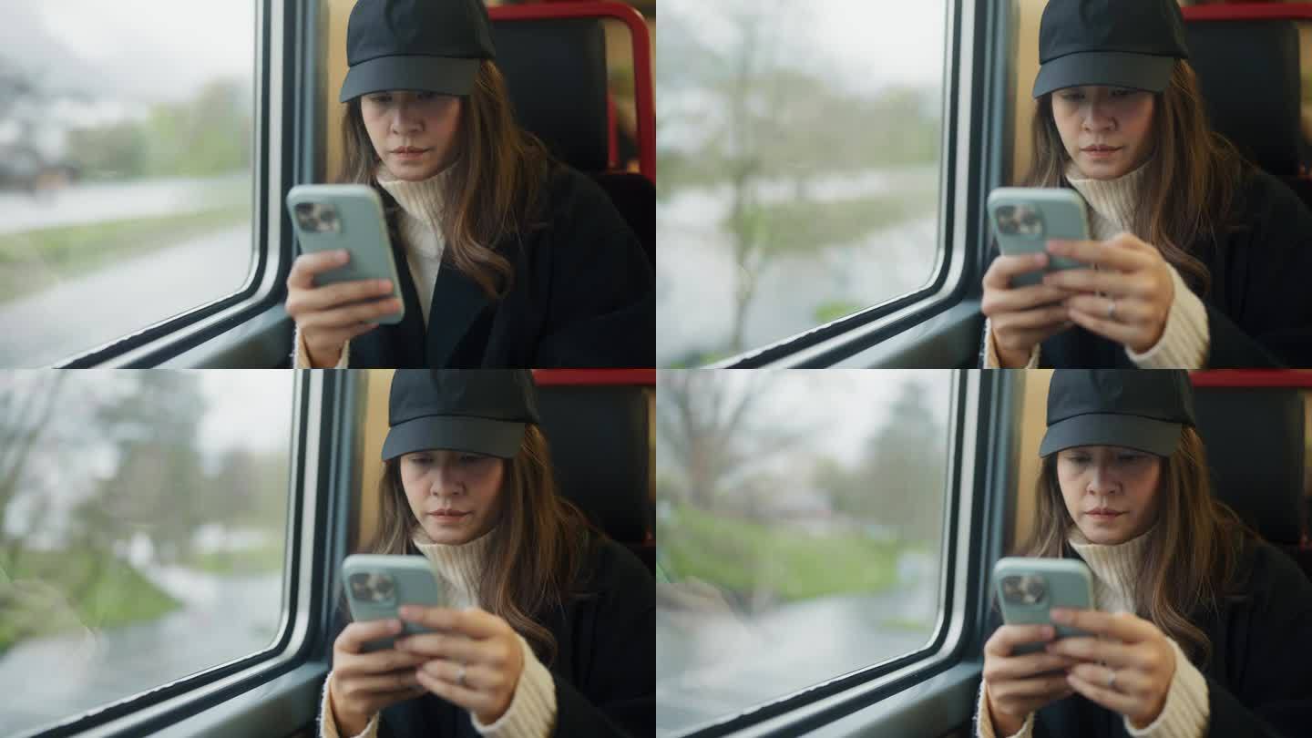 坐火车旅行时，放松的女游客坐在窗边玩智能手机，浏览社交媒体。