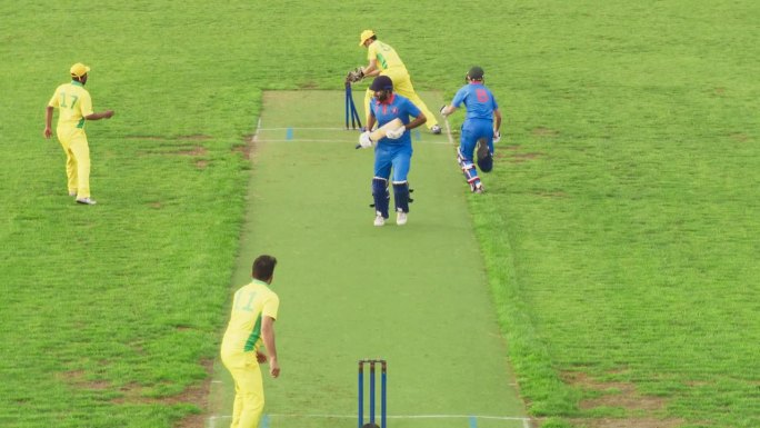 身穿黄色制服的球队在电视直播中庆祝胜利。南亚职业球队在板球锦标赛前训练。蓝队击球手没能跑过球场