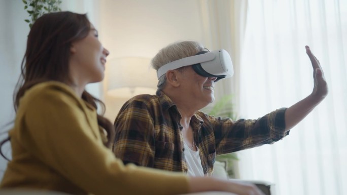 上了年纪的时尚花白头发的男人在客厅里和女儿坐在一起，用头盔应用程序玩模拟虚拟现实VR游戏。
