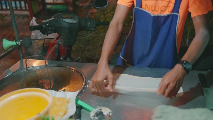 在泰国的夜市上，一个面目全非的男人在做烤饼