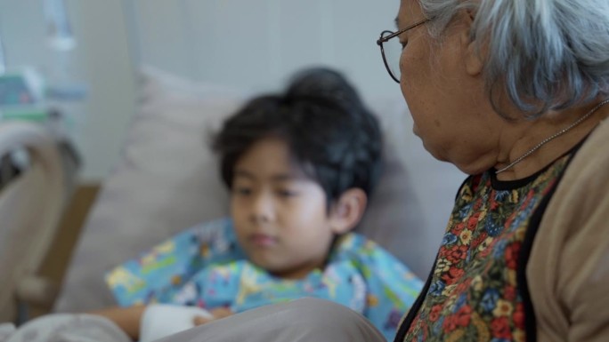 一位年长的亚洲妇女正在和她得了流感住院的孙子说话。