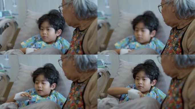 一位年长的亚洲妇女正在和她得了流感住院的孙子说话。
