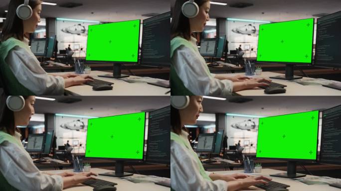 亚洲女性游戏程序员在游戏开发工作室办公室用绿屏Chromakey在台式电脑上编程。专注女性为新3D 